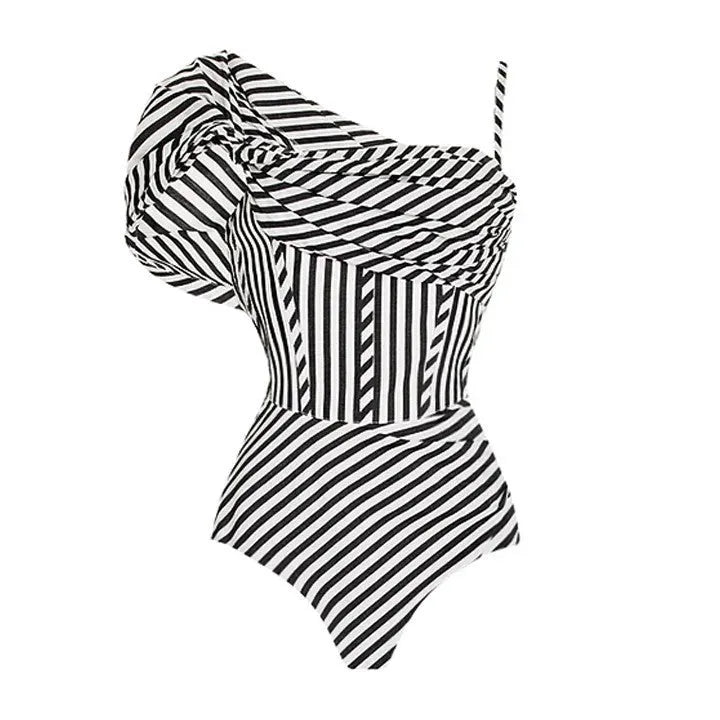 Woman wearing a striped one-piece swimsuit with a black ruffled skirt attached.