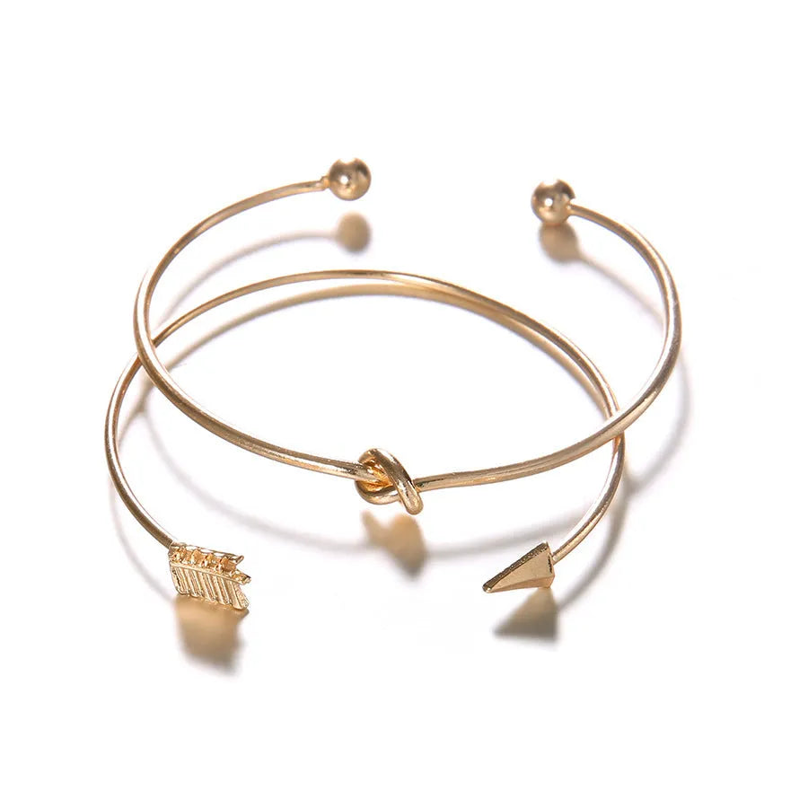 Gold electroplated vintage women's cuff bracelet with arrow and knotted design.