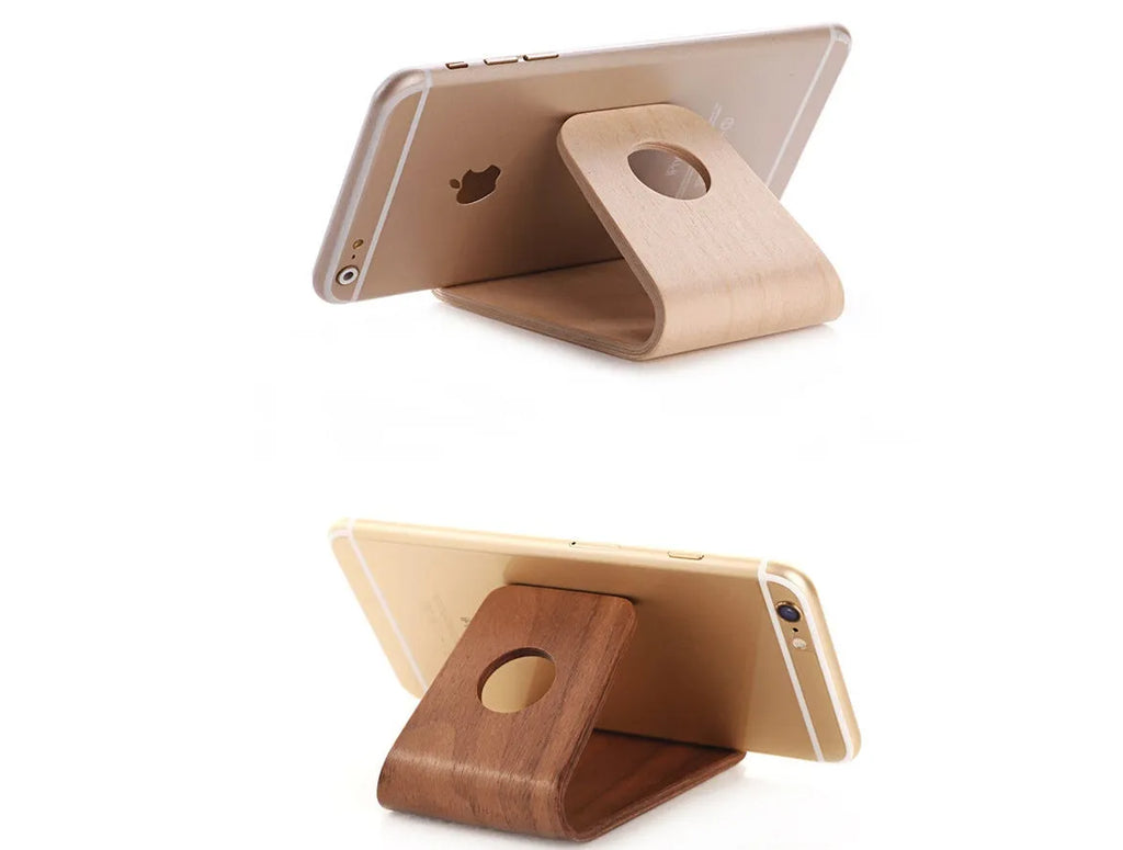 Solid walnut wooden stand holding an iPhone with charging cable routed through integrated channel
