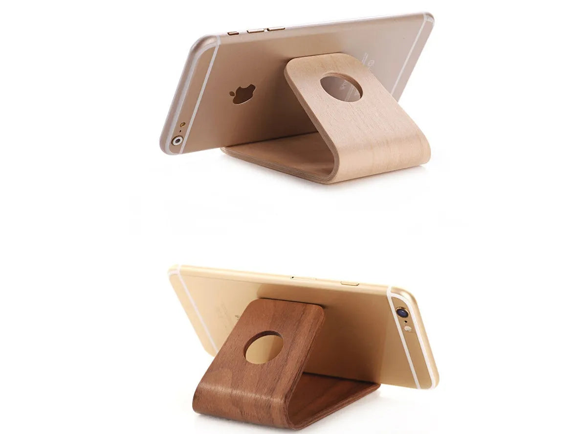 Solid walnut wooden stand holding an iPhone with charging cable routed through integrated channel