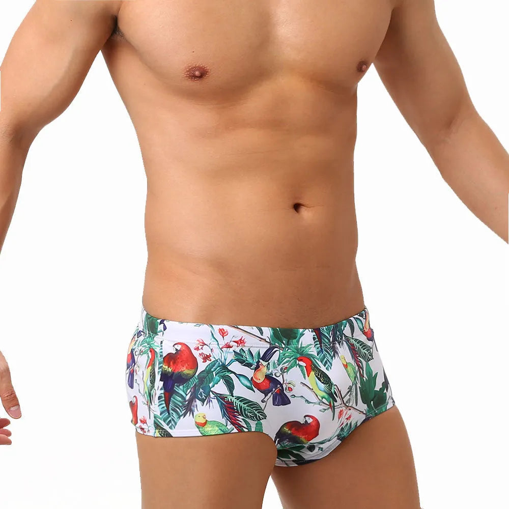 Men's blue swimming trunks with a colourful flowers and birds print, showing the boxer style and cup cover.