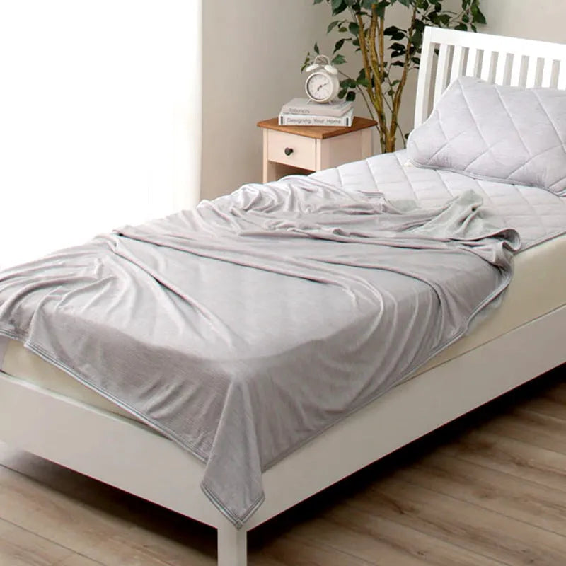 Blue cooling blanket with Japanese Q-Max fibres on a bed.