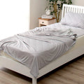 Blue cooling blanket with Japanese Q-Max fibres on a bed.