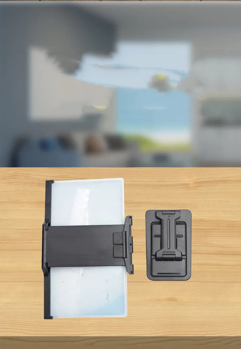 Black folding mobile phone screen magnifier with detachable holder next to an iPhone