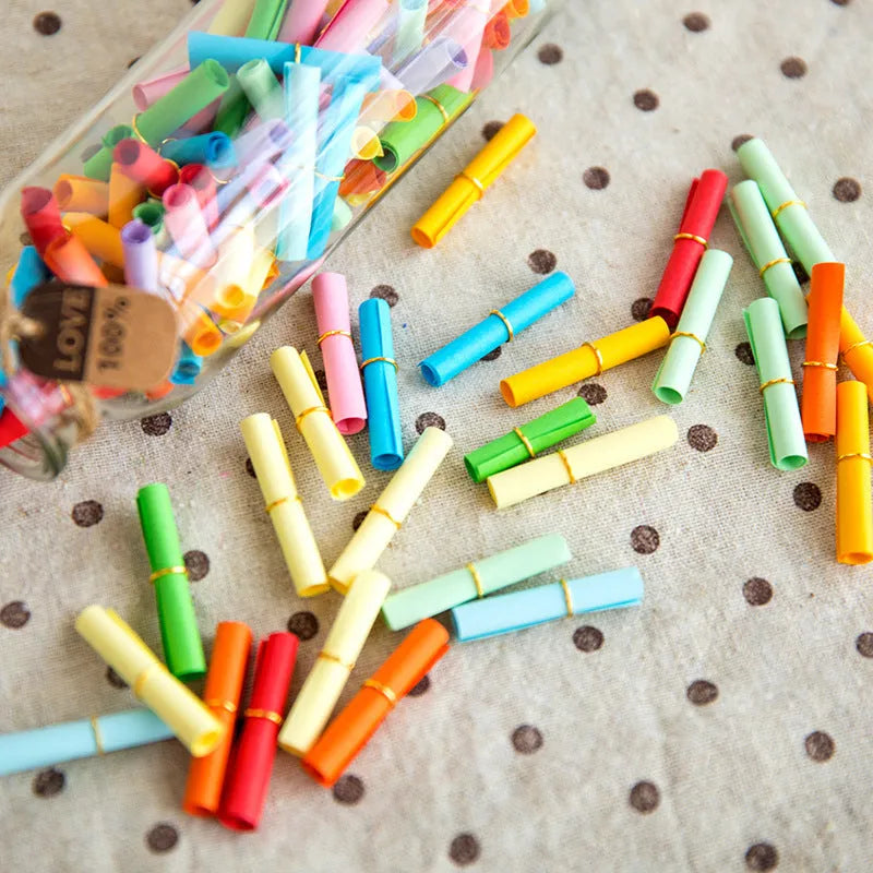 Assorted coloured paper scrolls in small sizes with a metal eyelet for hanging.