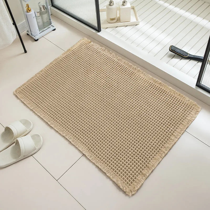Beige and white checkered woven polyester bathroom floor mat on tiles.