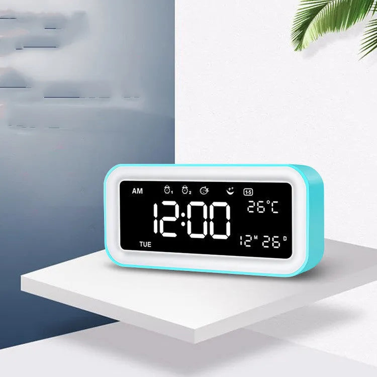 Blue rectangular LED digital alarm clock with multicoloured lighting and Bluetooth speaker on a bedside table.