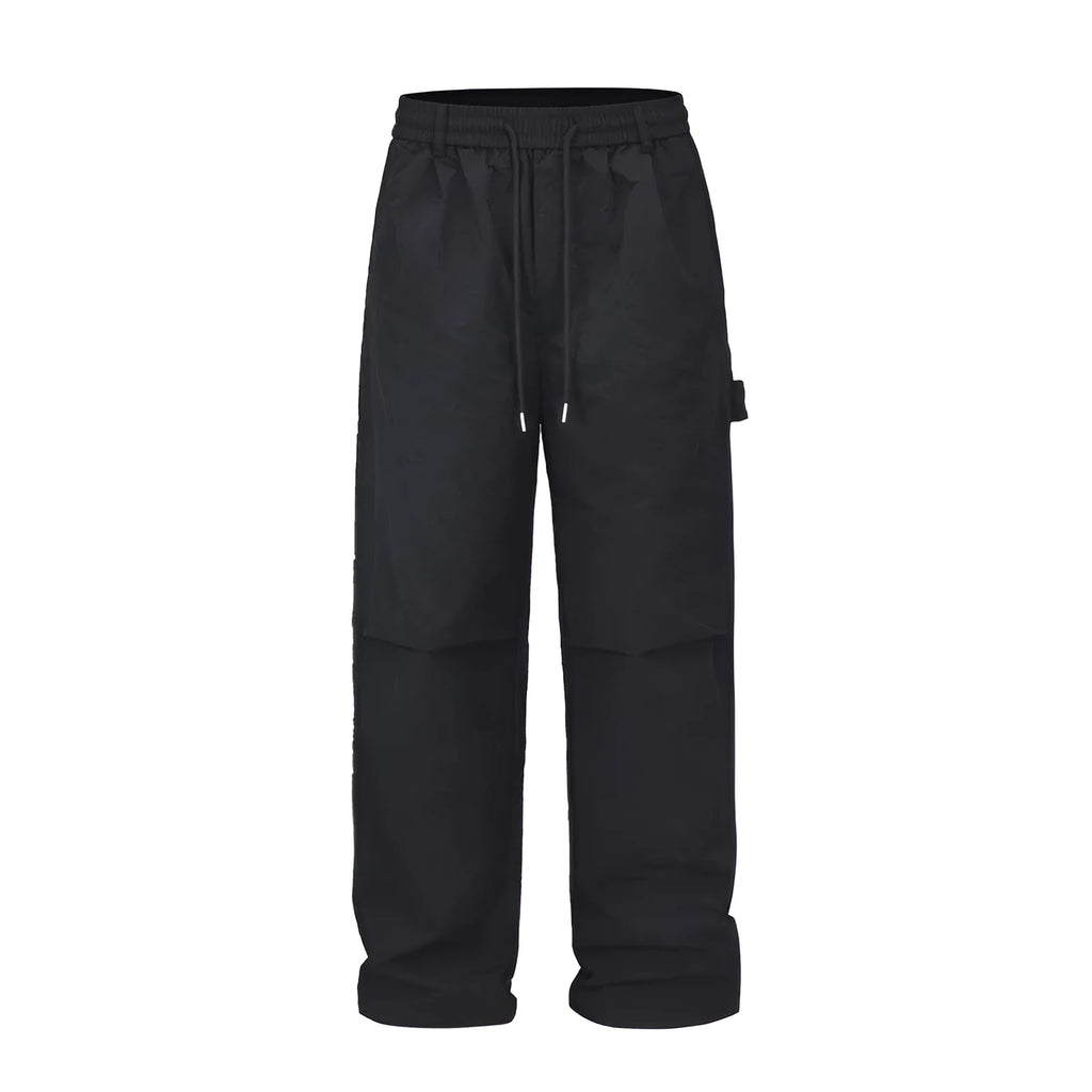 Black men's baggy paratrooper pants with an elastic drawstring waist on a neutral background.