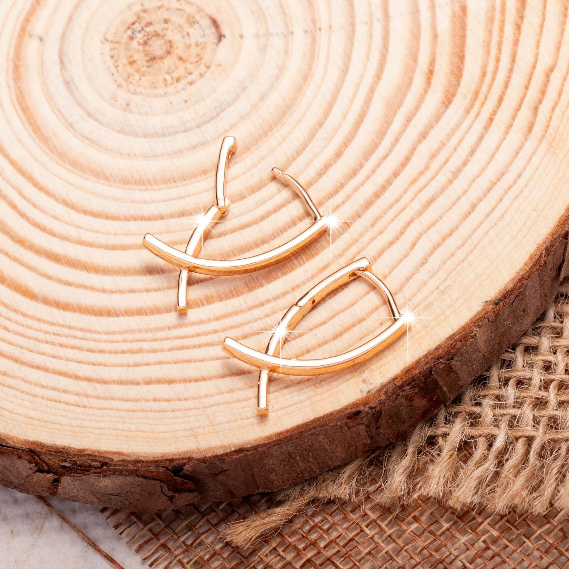 A pair of rose gold coloured cross-shaped stud earrings on a plain background.