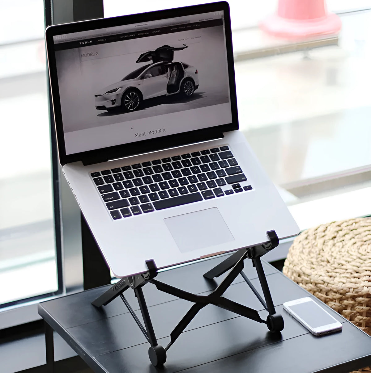Black folding portable laptop stand made of reinforced nylon, shown in folded position.