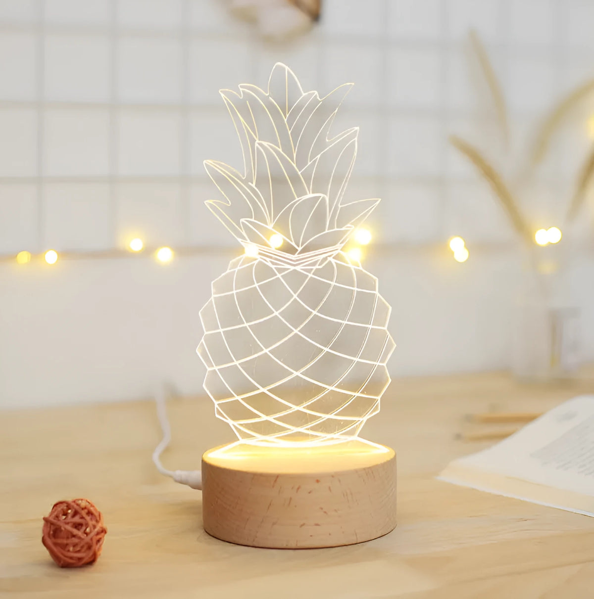 Cartoon pineapple-shaped night light with wooden base and acrylic shade on a table.