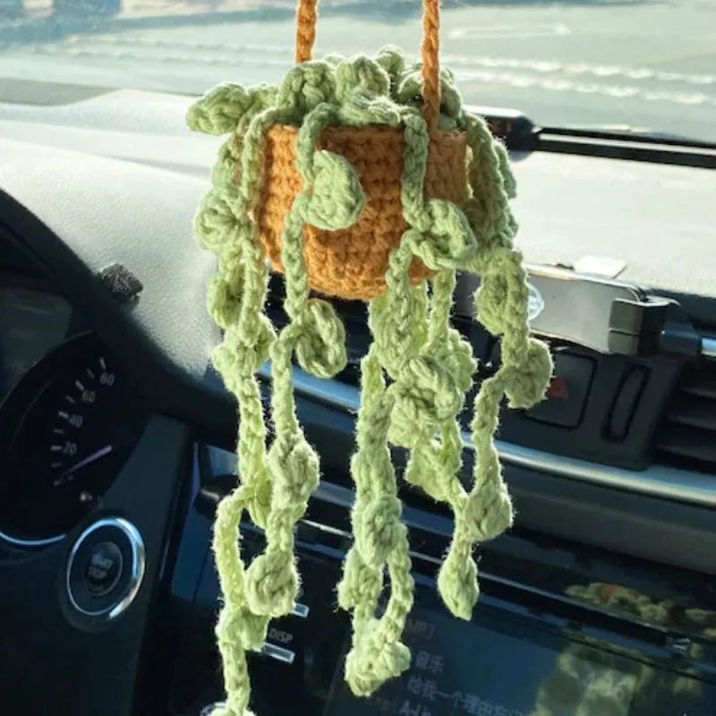 Green and white knitted wool car plant ornament with basin base and hanging rope.