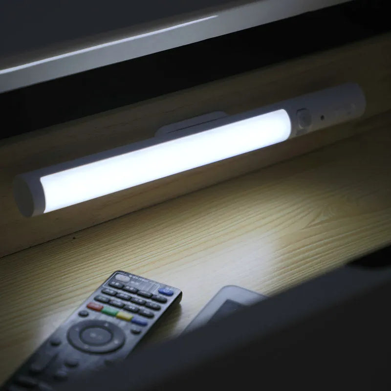 Slender white human body induction cabinet light with magnetic strip for mounting on metallic surfaces.