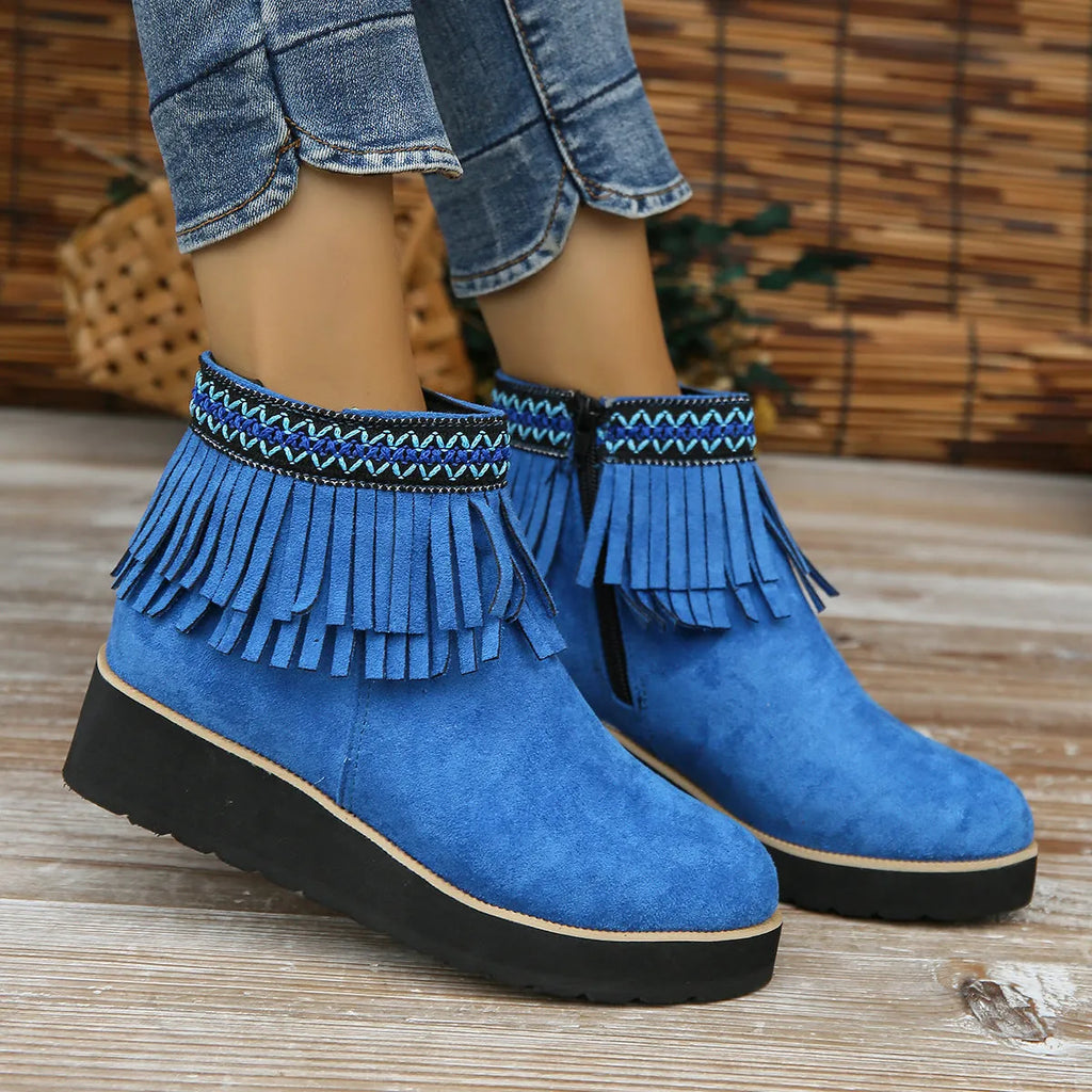 Women's suede ankle boot with wedge heel, side zipper, tassel detail, and thick rubber sole in three colour options.