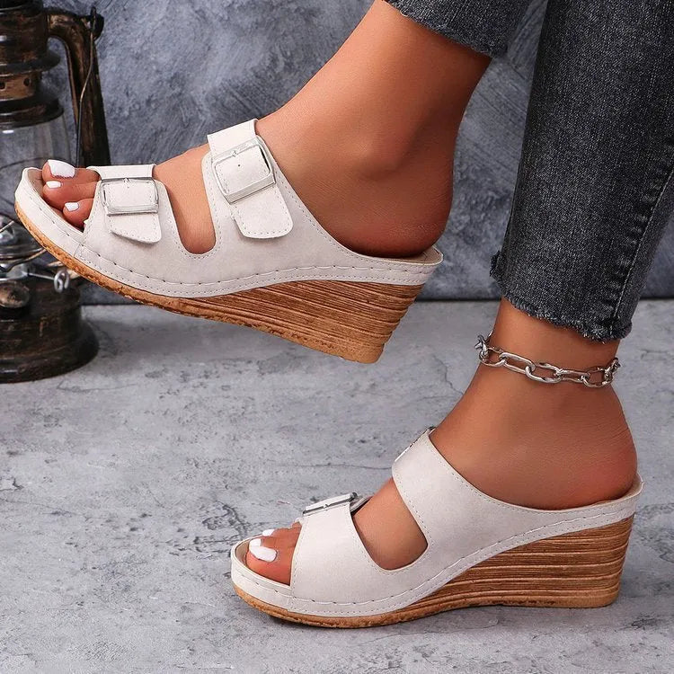 Women's wedge slippers with an outer buckle closure in creamy-white colour on a rubber sole.