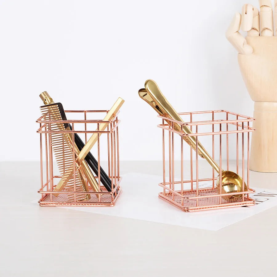 Rose gold iron wire square pen holder on desk holding pens and a ruler
