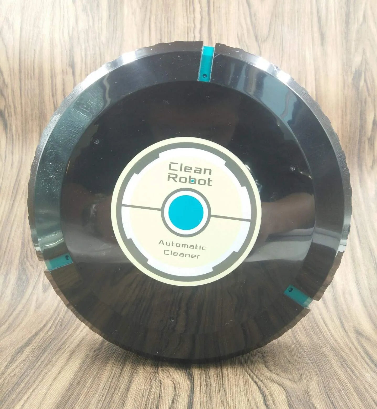 Black or white AC automatic sweeping robot on a hardwood floor next to a dust bin.