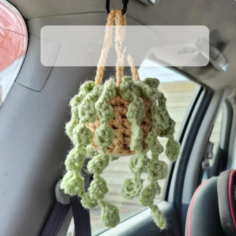 Green and white knitted wool car plant ornament with basin base and hanging rope.