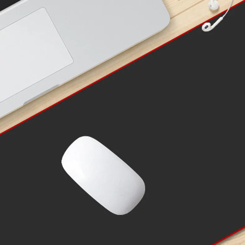 Extra long black mouse pad with stitched edges on a desk showing keyboard and mouse placement