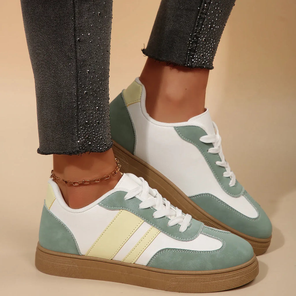 Green women's retro sneakers with cross-strap detail and leather stitching on a white background.