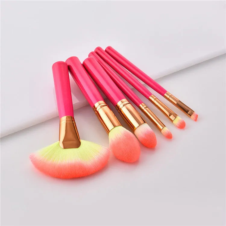 Pink cosmetic makeup brush set with wooden handles and synthetic nylon bristles on a flat surface