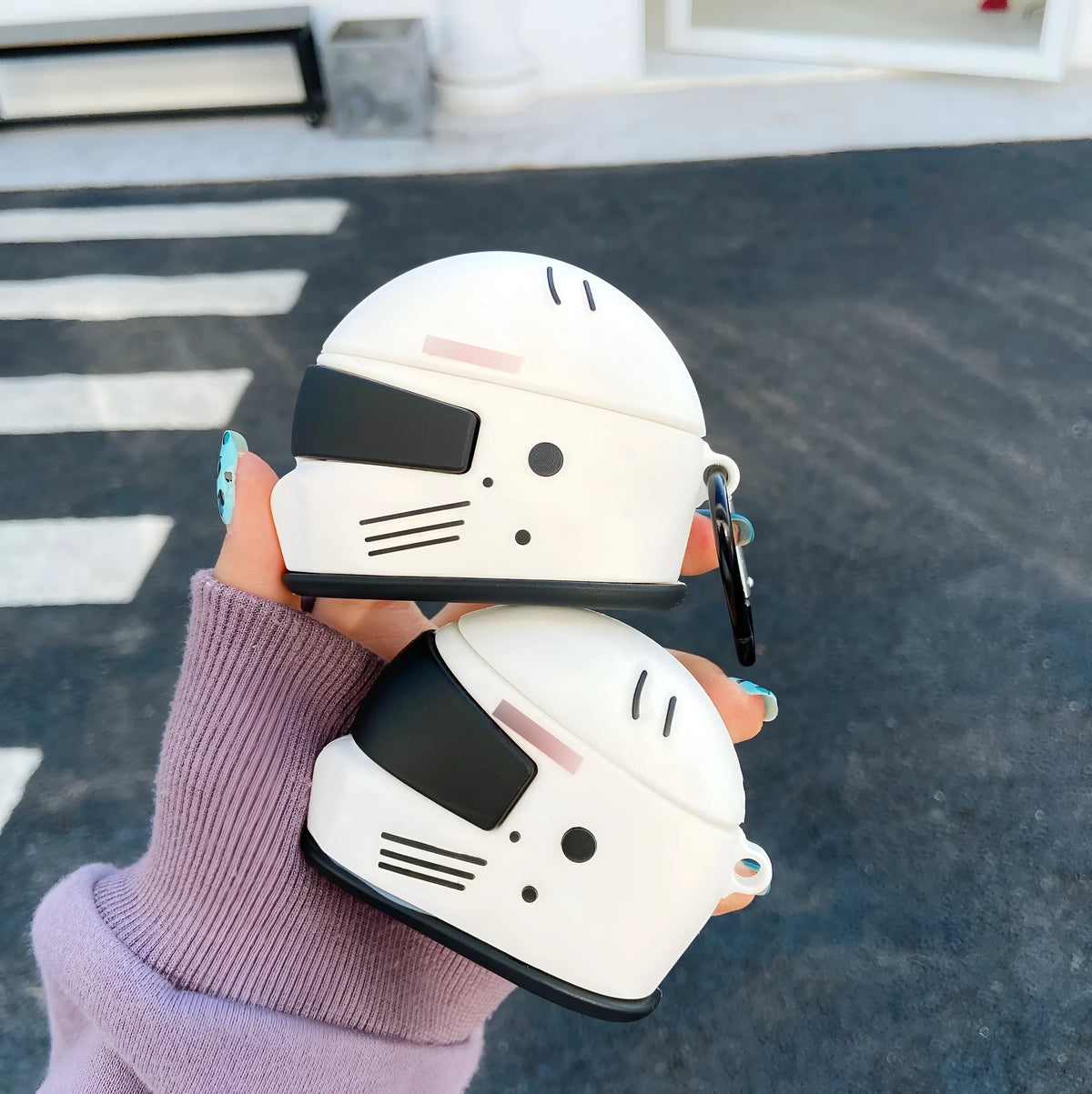 Black silicone AirPods case with motorcycle helmet shape, cartoon geometric design, and carabiner clip