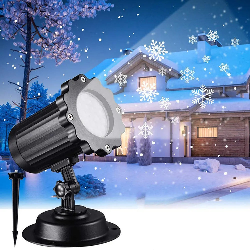LED Christmas snowflake laser projector with white moving patterns on a dark garden wall at night