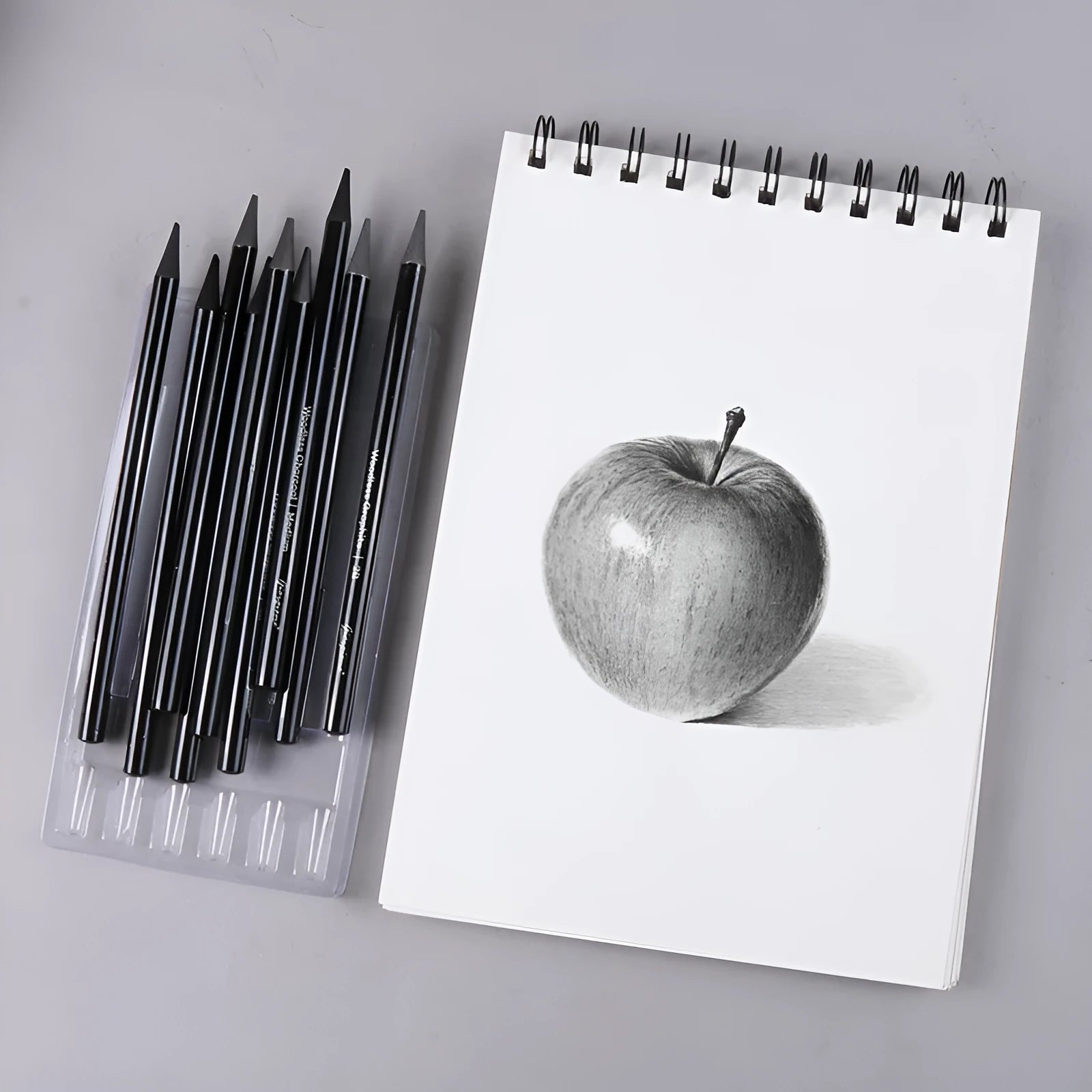 Set of six graphite and three carbonised drawing pencils with wooden shells on suction card packaging.