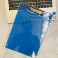 A4 transparent plate holder writing board with metal clip, shown in blue on a desk.