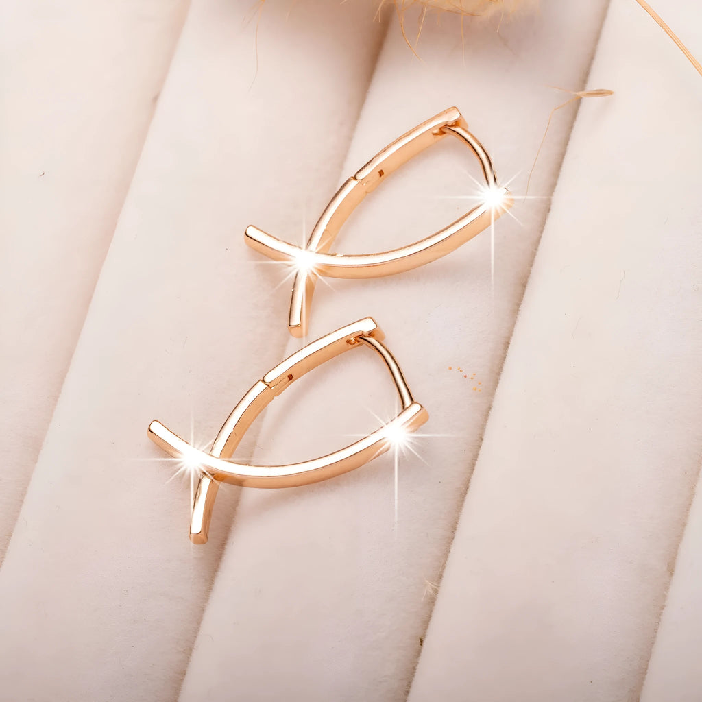 A pair of rose gold coloured cross-shaped stud earrings on a plain background.
