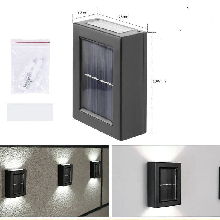 Small black solar-powered outdoor wall light mounted on a garden fence