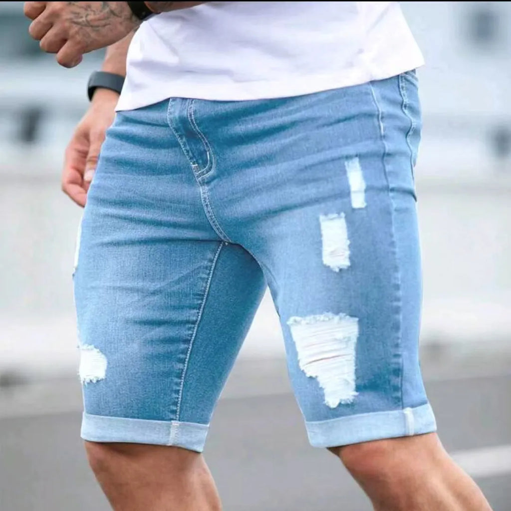 Men's sky blue denim shorts with distressed multi-hole design and straight leg cut