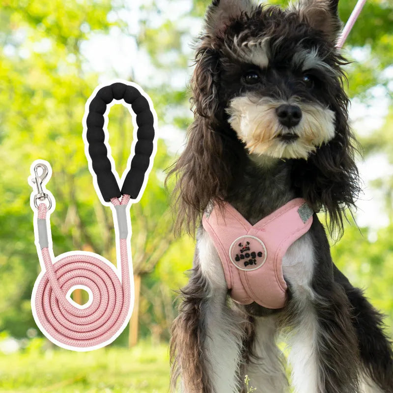 A pink polyester dog vest harness with an integrated hand holding rope laid flat.