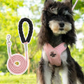 A pink polyester dog vest harness with an integrated hand holding rope laid flat.