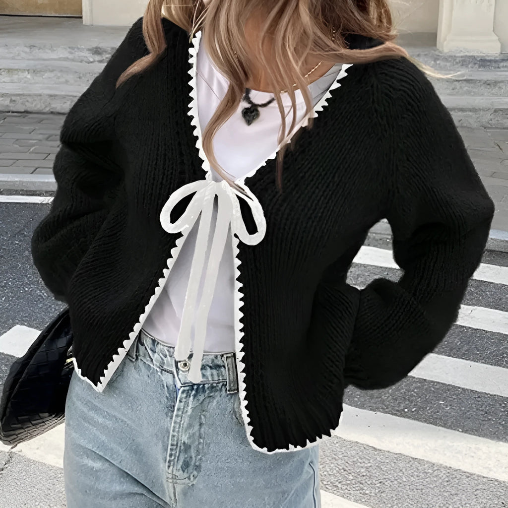 Gray lace-up cardigan sweater with crocheted flower detail and long sleeves on a hanger
