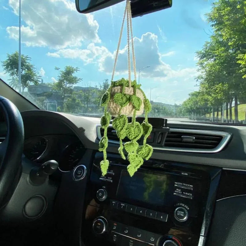 Green and white knitted wool car plant ornament with basin base and hanging rope.