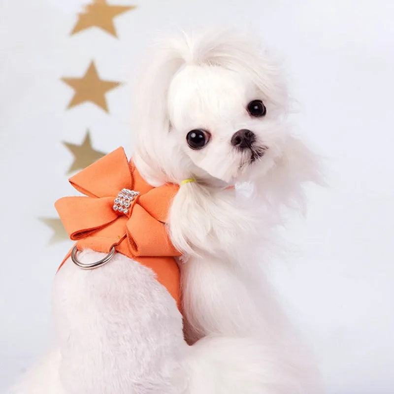 Pink microfiber dog harness with a large bowknot on the chest, shown alongside blue and orange colour options.