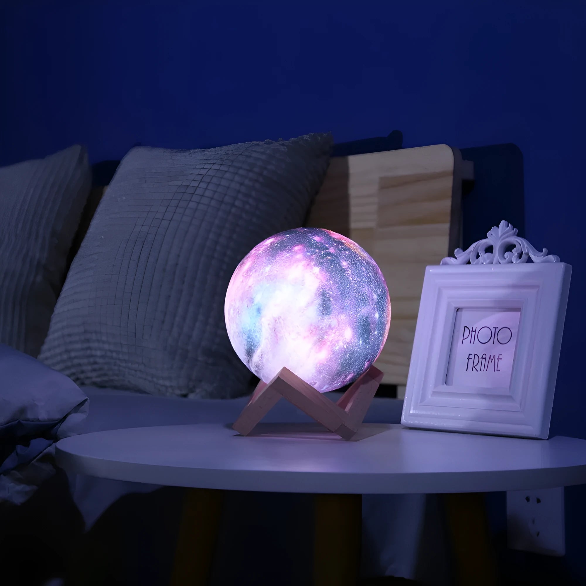 3D printed spherical moon night light glowing with multi-colour LED light on a dark surface.
