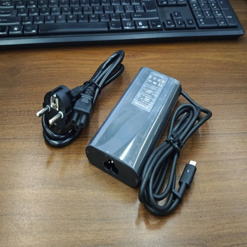 Black 65W USB-C laptop power adapter with UK plug and international travel adapters