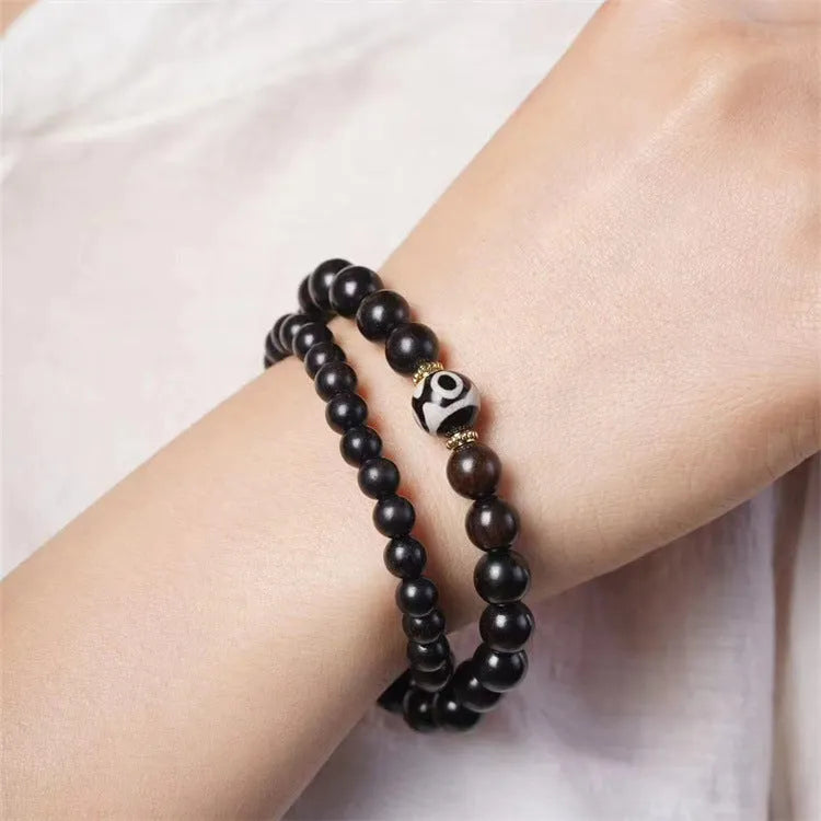 Close-up of a dark ebony wood bracelet with two smooth bead circles on a wrist.