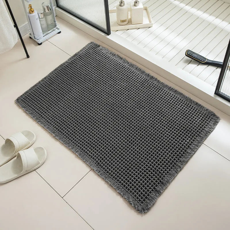 Beige and white checkered woven polyester bathroom floor mat on tiles.