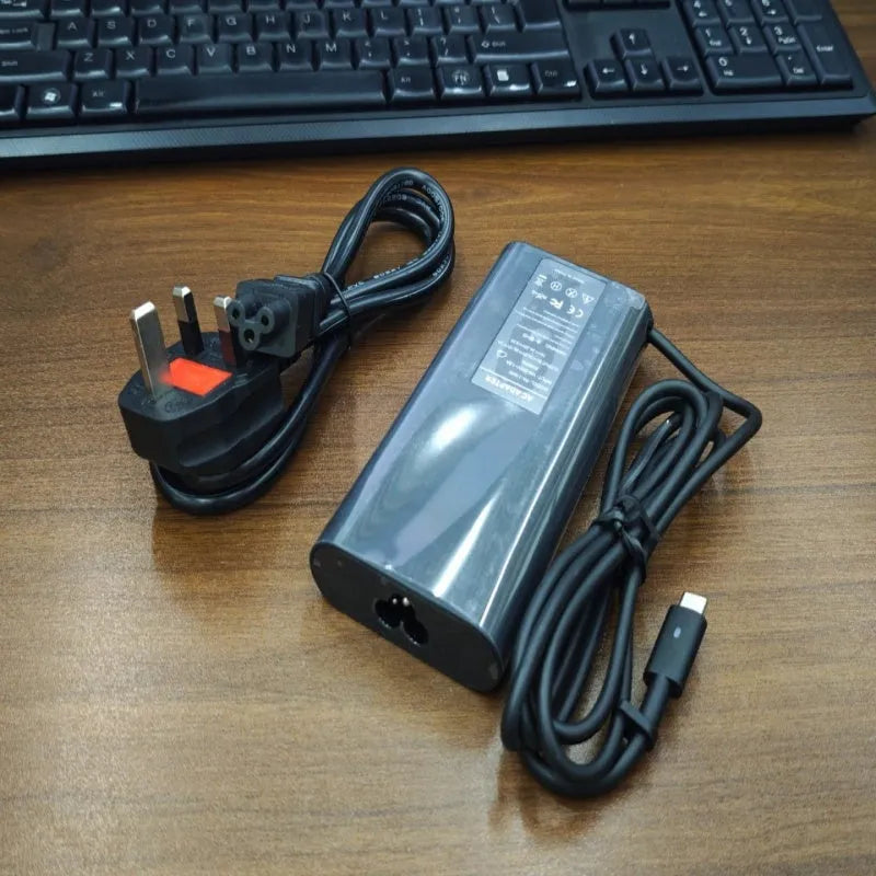 Black 65W USB-C laptop power adapter with UK plug and international travel adapters