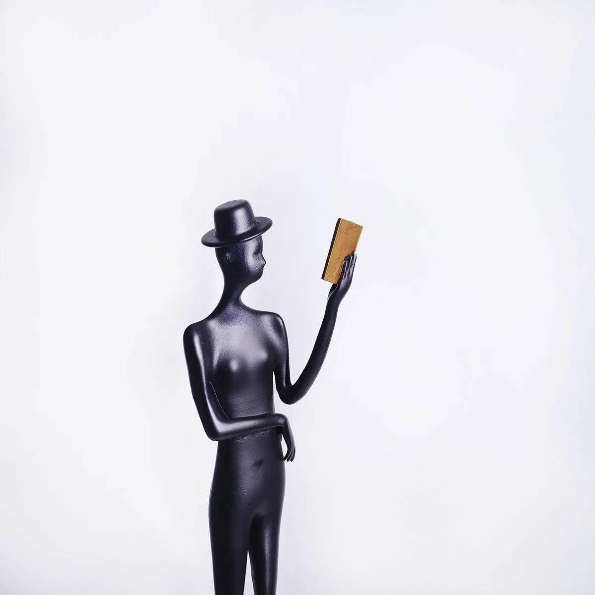 Black metal cast aluminium reading woman sculpture on desk, modern minimalist style