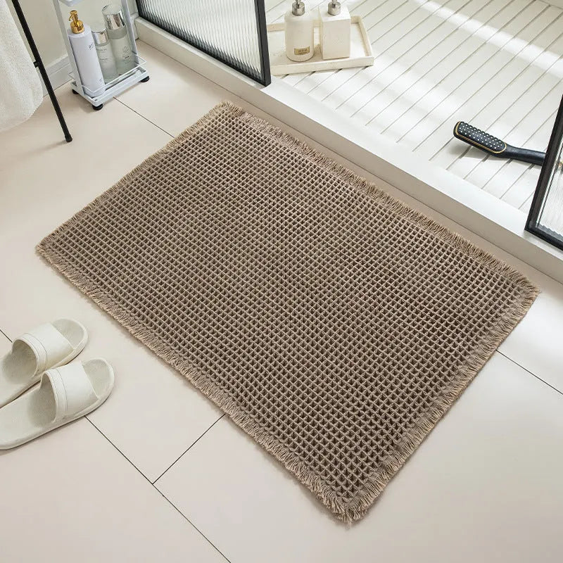 Beige and white checkered woven polyester bathroom floor mat on tiles.