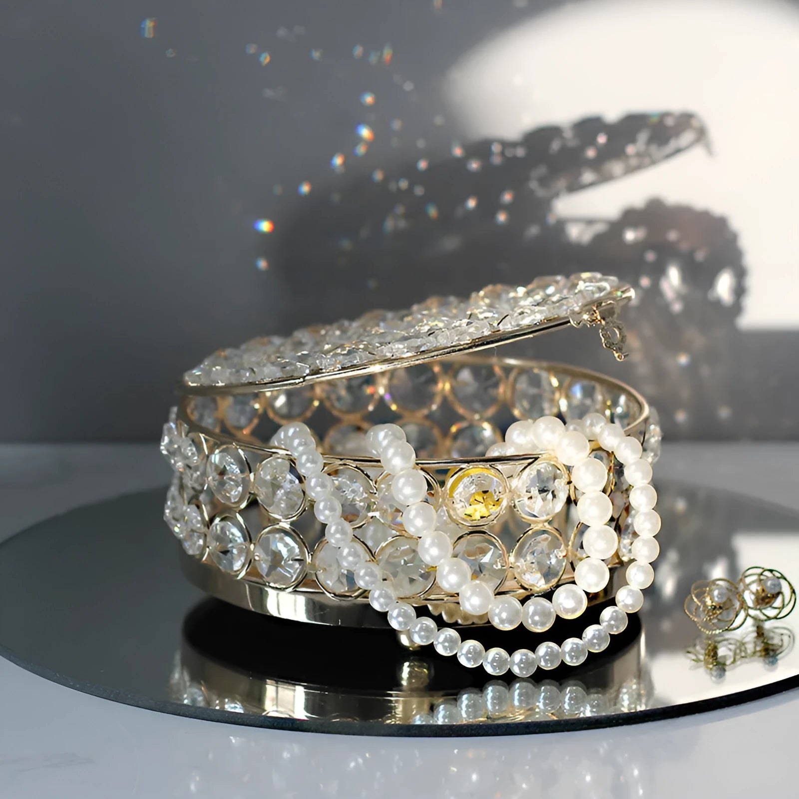 Transparent crystal glass jewelry storage box with ornate French gold metal frame.