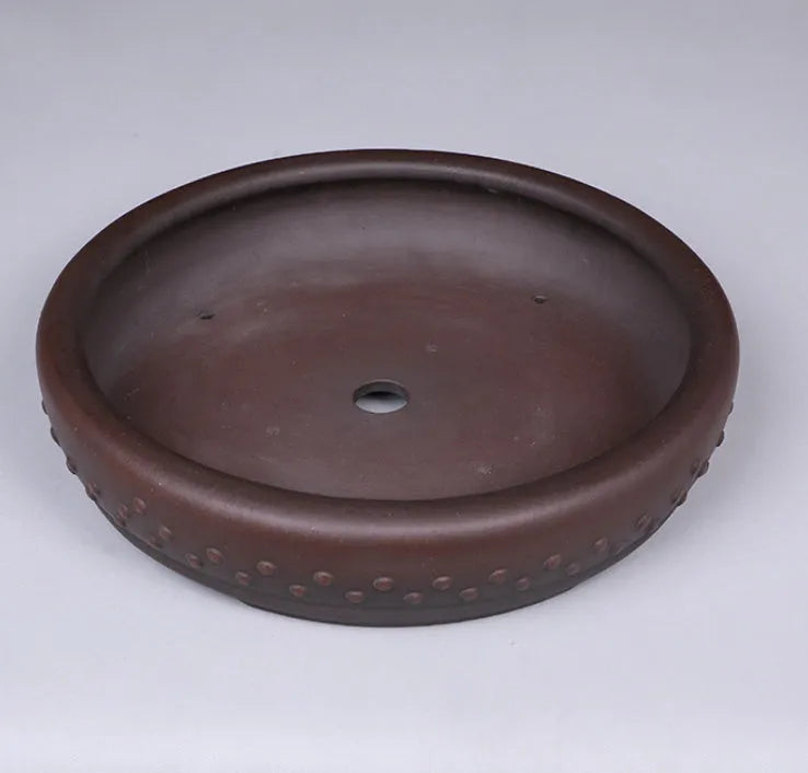 Classical handmade purple clay ceramic flowerpot with large round mouth on a wooden table