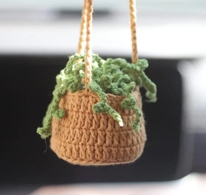 Green and white knitted wool car plant ornament with basin base and hanging rope.