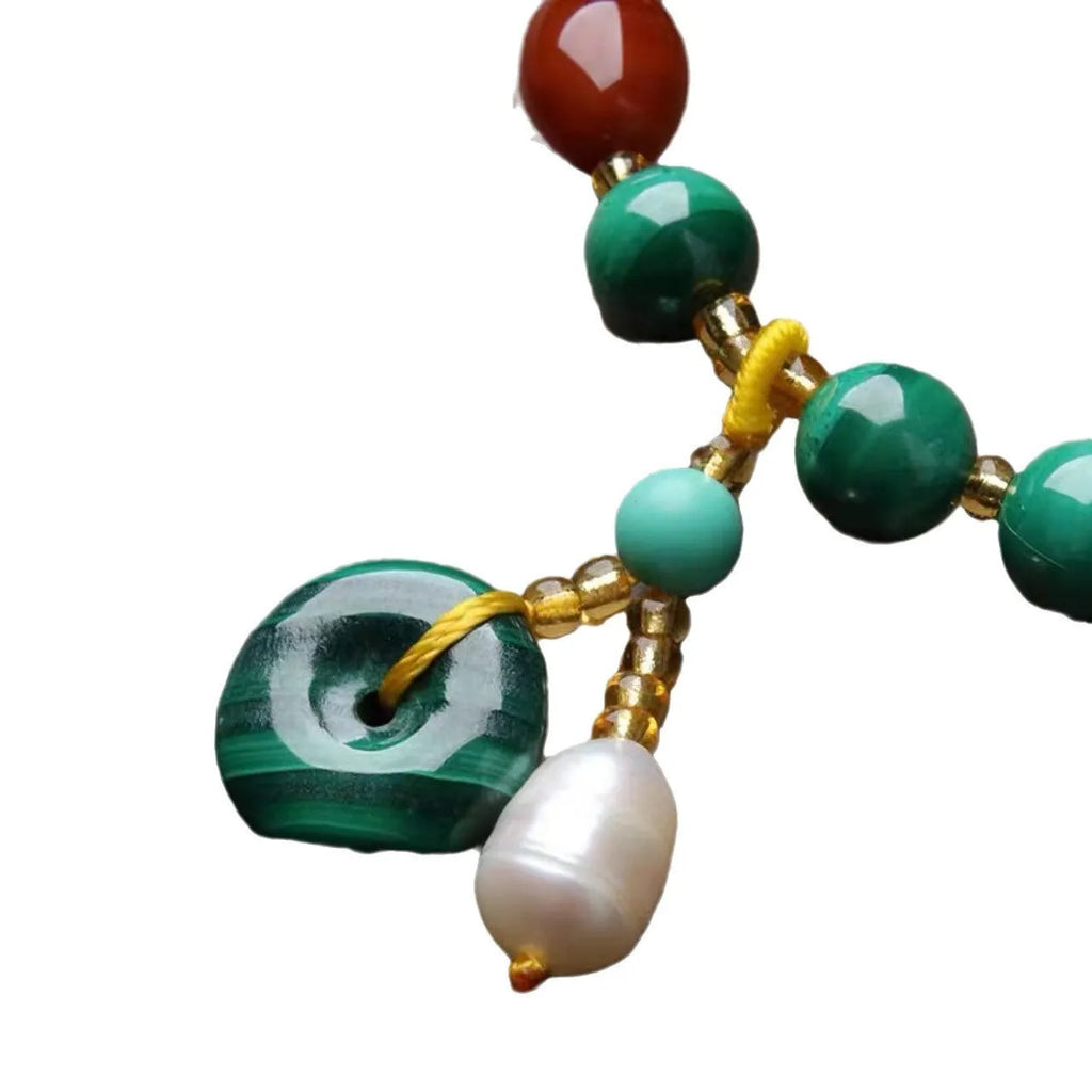 Natural green malachite bracelet with barrel-shaped beads on a wrist.