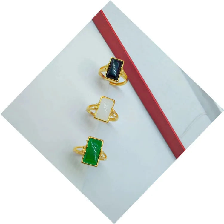 Adjustable gold-plated brass ring with a black electroplated gemstone on a neutral background.