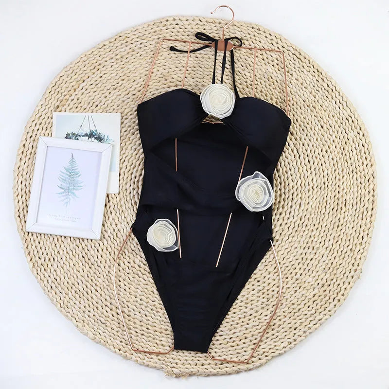 Women's black one-piece swimsuit with 3D white flower detail on the front